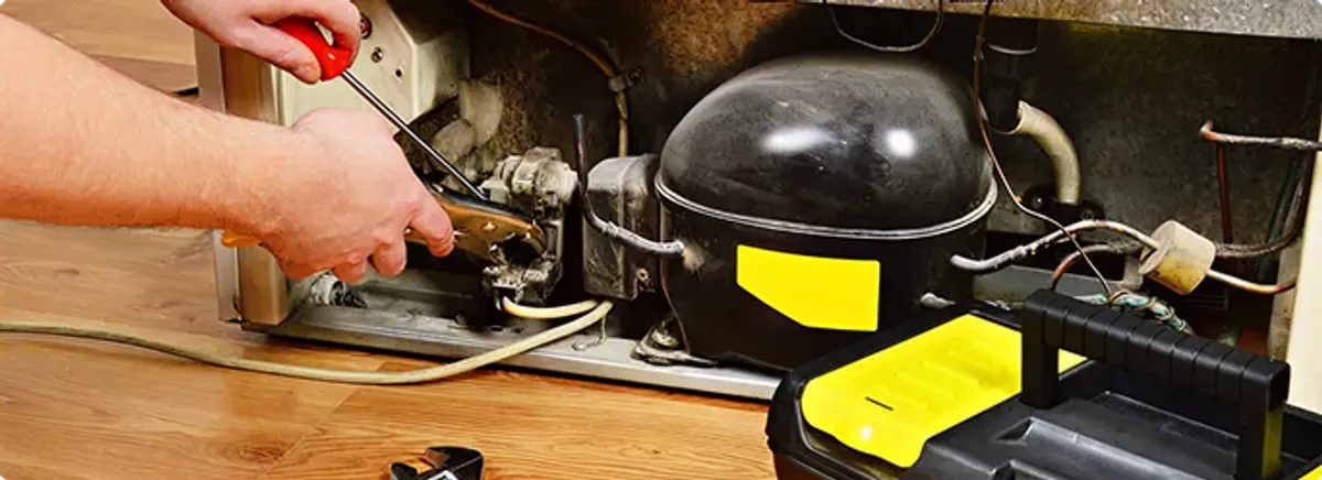 Refrigerator repair technician fixing the compressor and wiring in Opa Locka, FL
