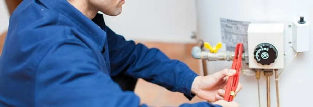 Water heater repair technician adjusting the temperature control and gas valve in Miami, FL